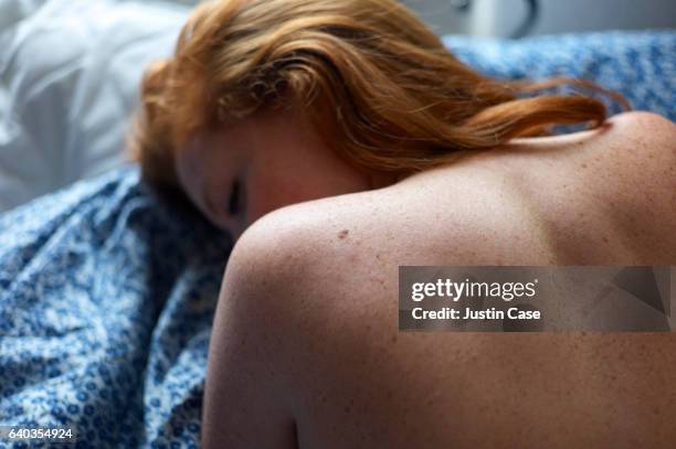 woman on bed showing her naked shoulders with freckles - auf dem bauch liegen stock-fotos und bilder
