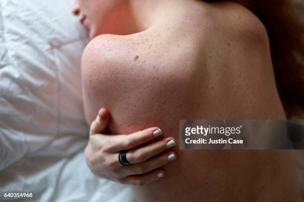 shoulders and hand of a woman with freckled skin - berühren stock-fotos und bilder