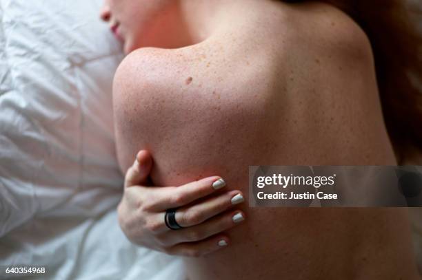 shoulders and hand of a woman with freckled skin - women touching herself in bed stock pictures, royalty-free photos & images