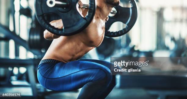um homem fazendo agachamentos em uma academia. - muscular contraction - fotografias e filmes do acervo