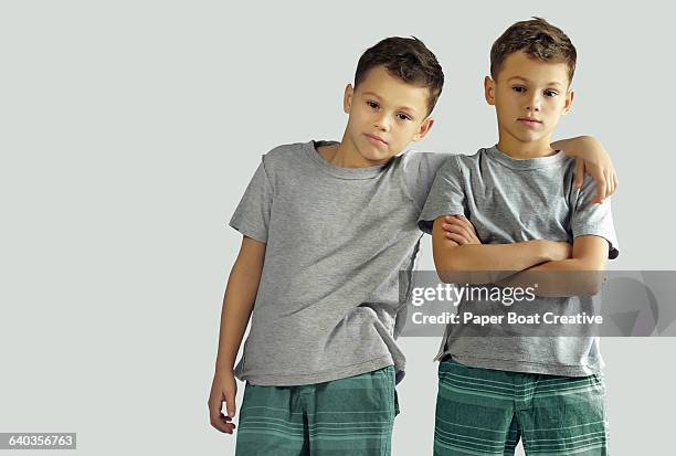 two identical twin brothers standing together - twins boys stock pictures, royalty-free photos & images