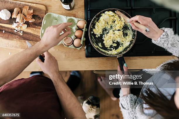 overhead view of couple making eggs - roerei stockfoto's en -beelden