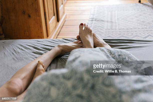 first person perspective of couple in bed - feet in bed stock-fotos und bilder