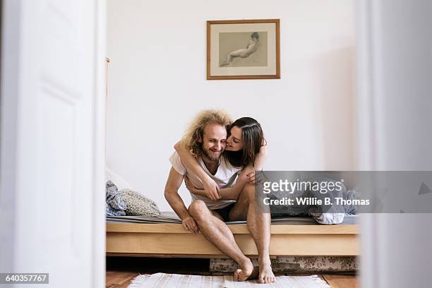 couple sitting on bed hugging - bright bedroom stockfoto's en -beelden