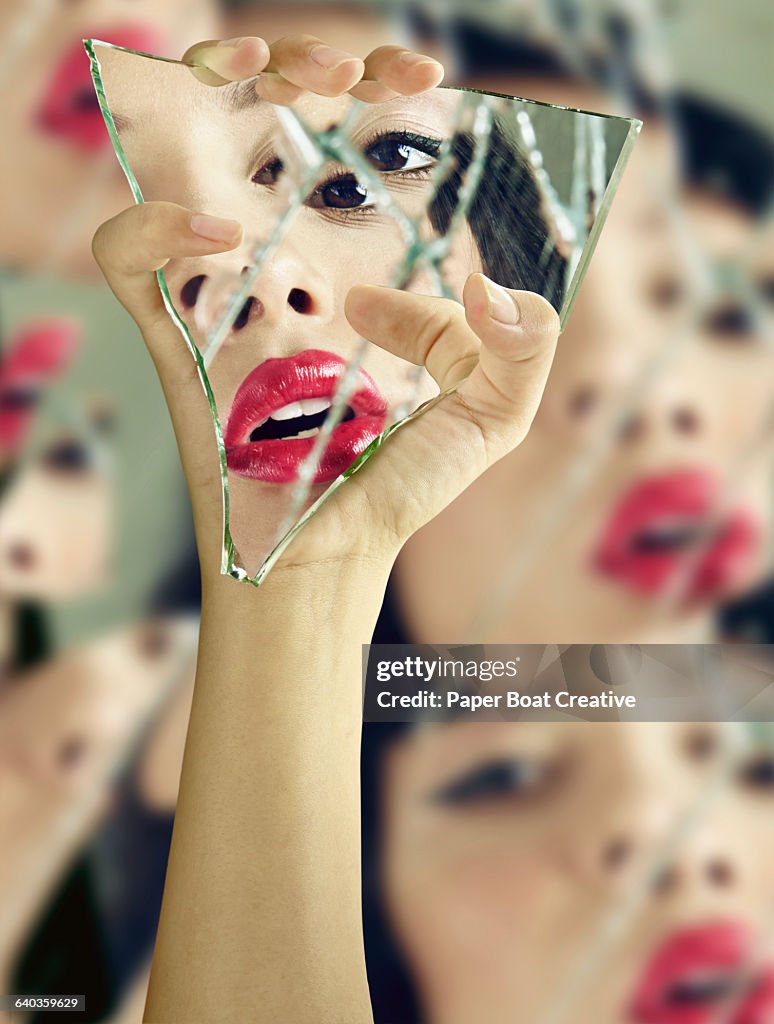 Vain woman checking her lipstick in broken glass