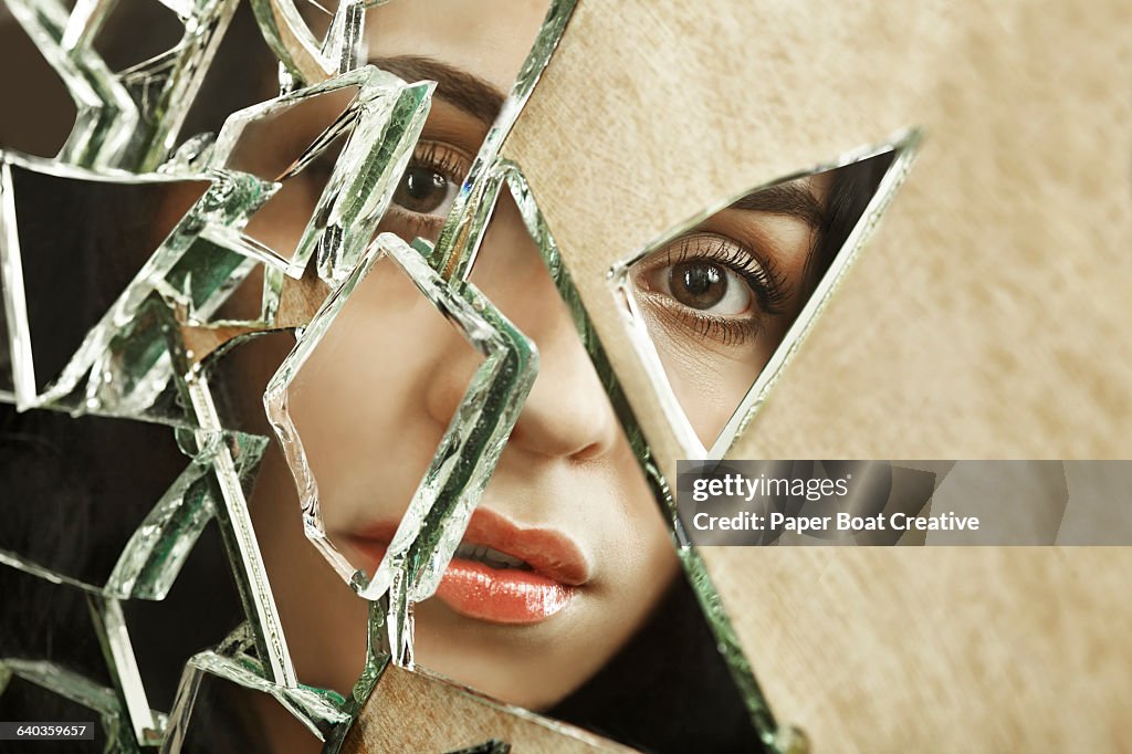 Close up of a woman looking through broken glass