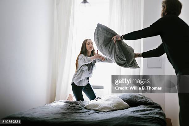 young couple playful making bed - making bed stockfoto's en -beelden