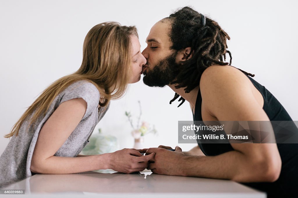 Interracial Couple kissing at Kitchen table