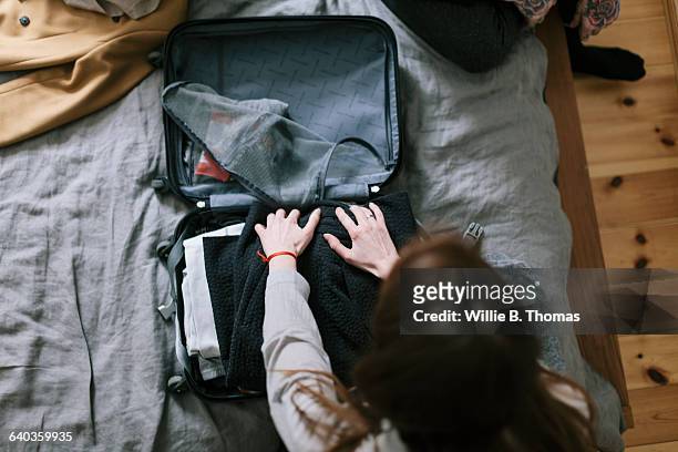 woman packing a suitcase - suitcase stock pictures, royalty-free photos & images
