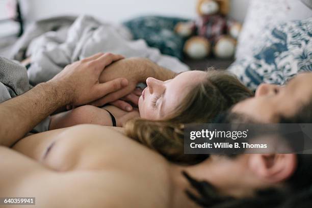 interracial couple sleeping together in bed - man and woman cuddling in bed stock-fotos und bilder