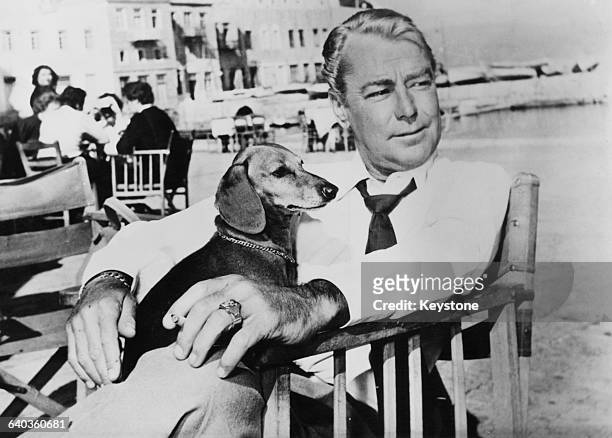 American actor Alan Ladd relaxes with his pet dog on the Greek island of Hydra, after location shooting of the exterior shots for the film 'Boy on a...