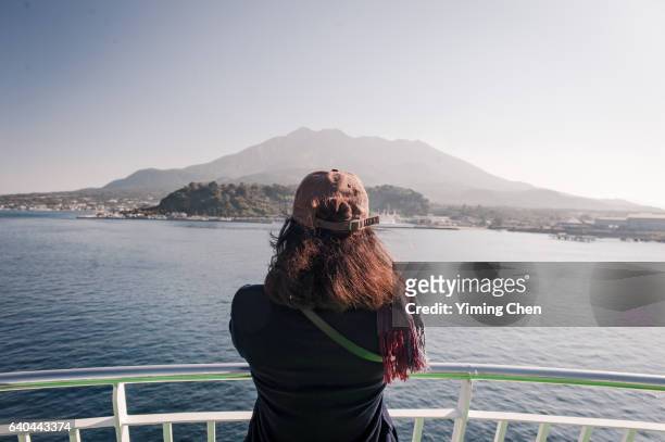 tourist on ferry ship looking at sakurajima volcano - îles ogasawara photos et images de collection