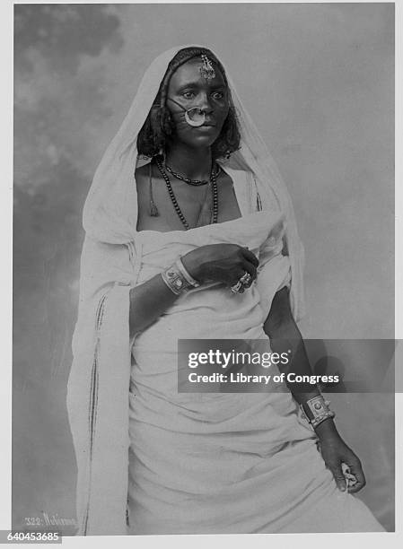 Sudanese woman poses wearing bracelets, rings, a beaded necklace and a metal nose ring. Sudan.