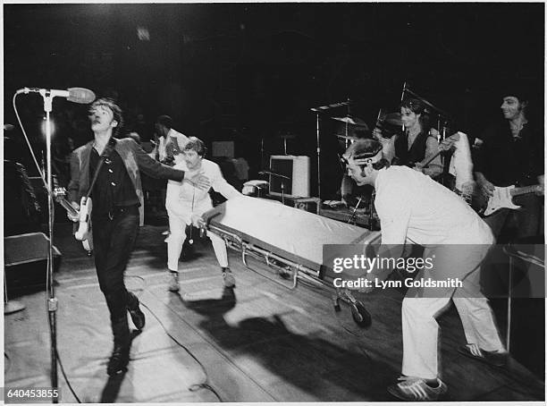 Men in white jackets place a stretcher behind Bruce Springsteen as he feigns collapsing on stage on his 30th birthday during his 1979 MUSE concert.