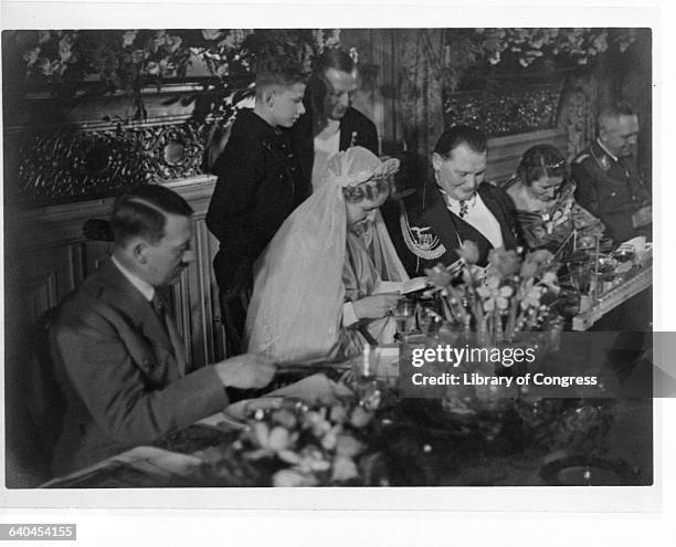 Adolph Hitler sits with the bridal party at the wedding of Hermann Goering and Emmy Sonnemann.
