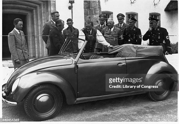 Hermann Goering stands next to a Volkswagen convertible at Carinhall hunting lodge, with Robert Ley and Ferdinand Porsche.