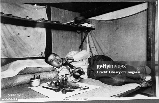 Opium Smoker Lying Down and Holding Pipe