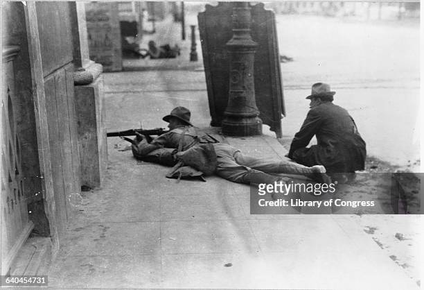 An United States Marine shoots his rifle with another man crouched behind him on the streets of Veracruz. The United States invaded Veracruz in 1914...