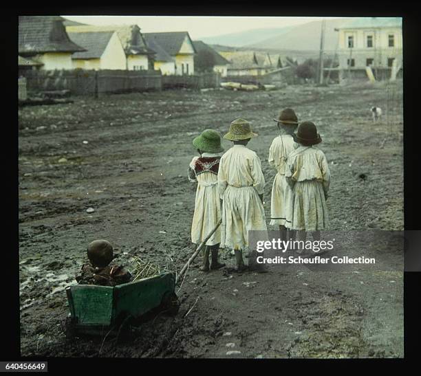 Group of children pull a baby along the ground in a cart in a field in Detva, Slovakia.