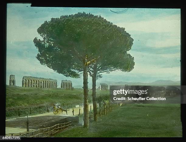 The ruined arcades a Roman aqueduct stand at the side of the Via Appia Atica road, near Rome. Italy, ca. 1907.