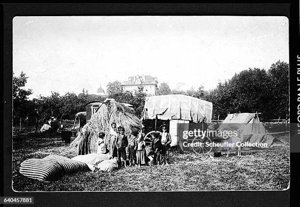 Gypsy family comprising a mother with her children stand outside their caravan and tent. | Location: Czech Lands.