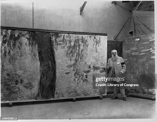 Claude Monet standing in his studio with a panel of his Nympheas mural. | Located in: Musee de l'Orangerie.