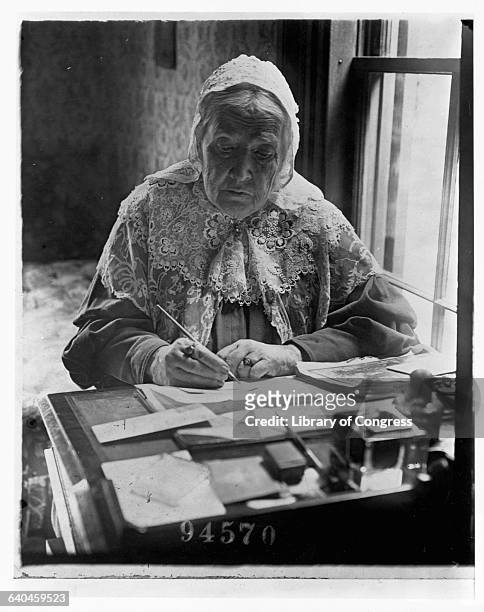Suffragist and author of the famous American poem "Battle Hymn of the Republic," Julia Ward Howe writes at a desk near a window.