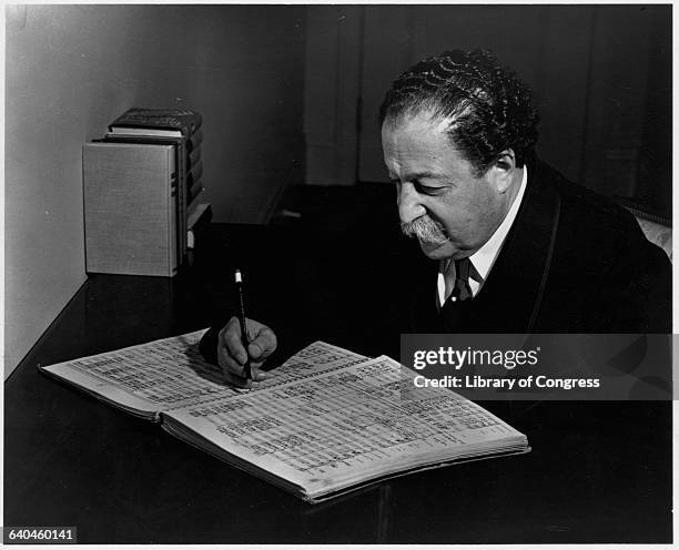 Conductor Pierre Monteux working in a notebook.