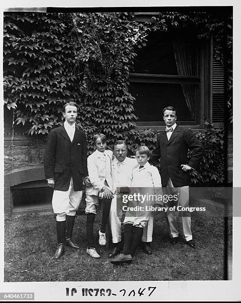 Portrait of President Teddy Roosevelt and his sons Theodore, Kermit, Quentin, and Archibald in a backyard.