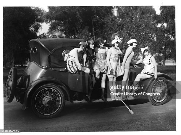 Seven bathing beauties from producer Mack Sennett's films stand on the running board of a car while they model swimwear.