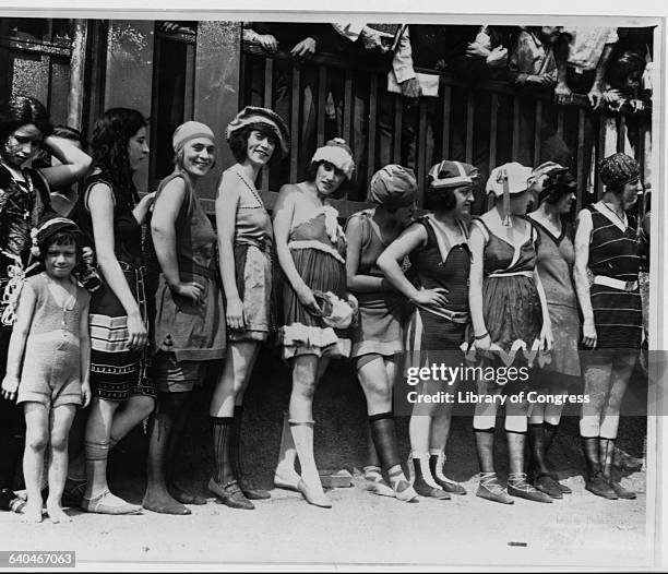 Group of women and a little girl, dressed in the latest in 1920s swimwear, line up for a bathing beauty contest.