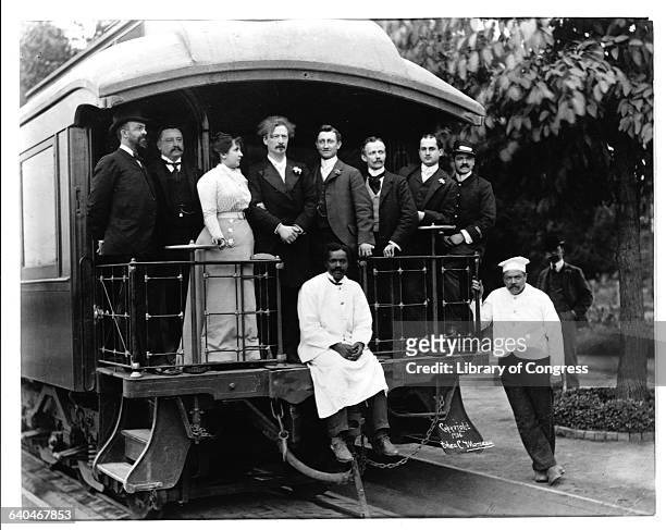 Pianist Ignacy Jan Paderewski and his wife Helena standing with a group of domestic workers on a the back of a passenger train.