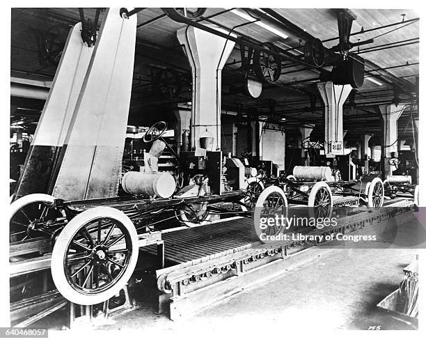 Line of Model T automobiles await further assembly. The Highland Park Ford Plant in Michigan is considered to be the birthplace of moving assembly...