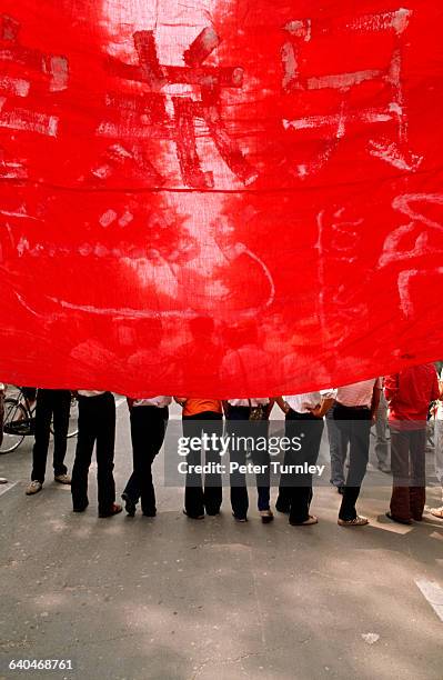 Chinese student protesters are partially obscured by a large red banner during the Tiananmen Square protests.