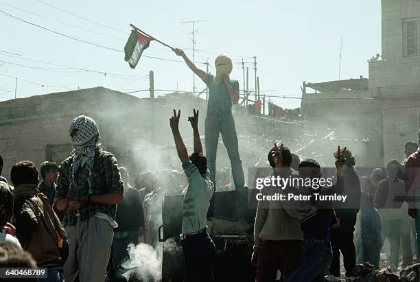 Young Palestinian freedom fighters give the sign for liberation and wave a flag during a riot against the occupying Israeli soldiers.