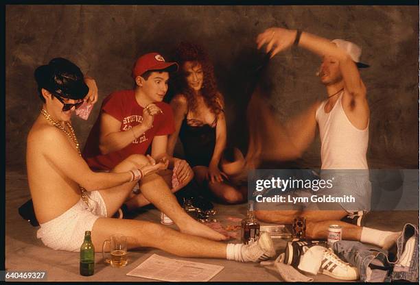 The Beastie Boys play strip poker and drink beer with a young woman in a black negligee.