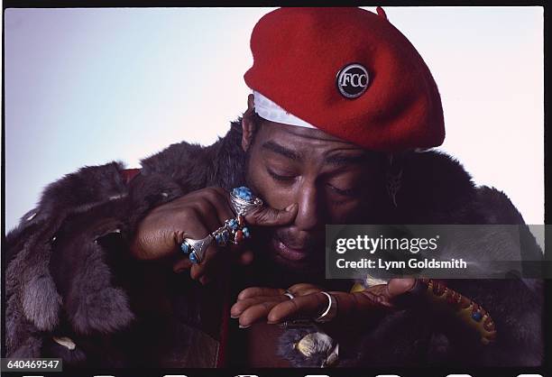 George Clinton pressing his finger against his nose pretending to snort cocaine from his hand.