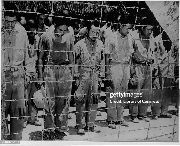 Japanese prisoners of war held at Guam bow their heads on August 14, 1945 as they listen to their Emperor announce the surrender of Japan to Allied...