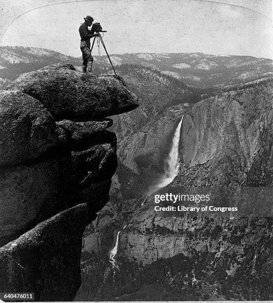 Photographer stands on an outcroping of rocks called Glacier Point some 3,300 ft above the Yosemite Valley, looking down at Yosemite Falls, 1902.