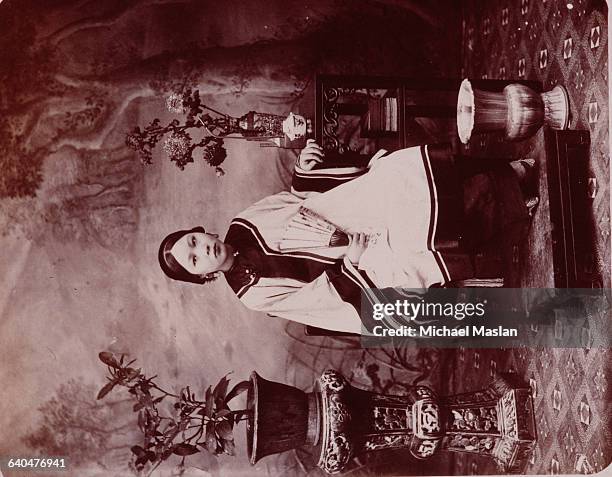 Portrait of young Chinese woman around the turn of the century whose tiny feet are the result of the Chinese tradition of foot-binding. China[?], ca....