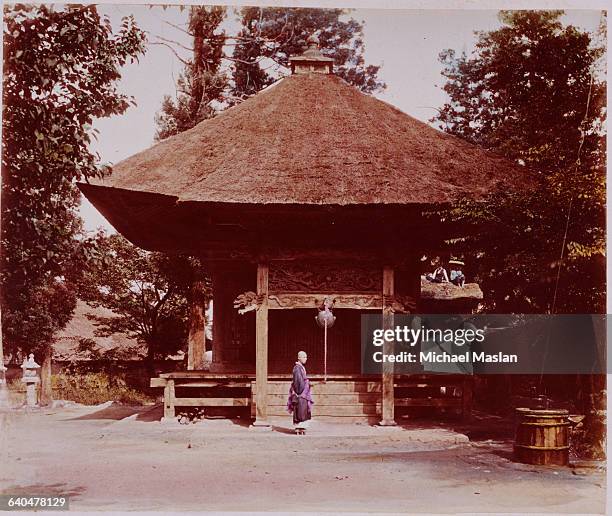 Monk stands outside a Shinto shrine. Japan, ca. 1910s-1920s.