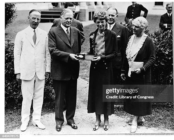 President Herbert Hoover presenting the National Geographic Society gold medal to Amelia Earhart in recognition of her continuous solo flight across...