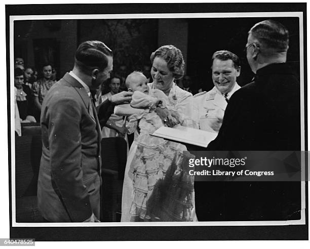 Hermann and Emmy Goering hold their daughter Edda at her christening, as Adolph Hitler tickles the baby. 1938.