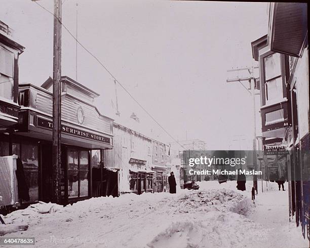 Downtown Front Street is piled with typical winter snow in Nome, Alaska. Ca. 1900-1920.