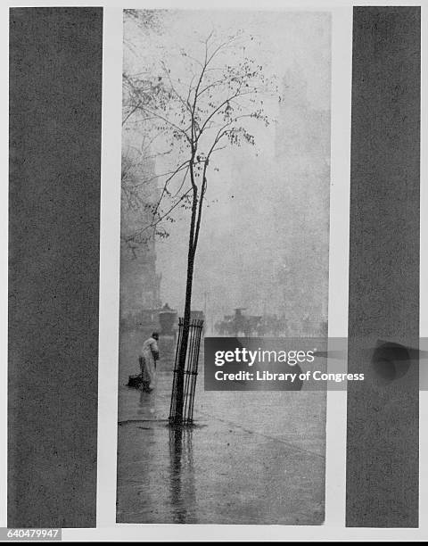 Man cleans a wet New York City street in The Sweeper by Alfred Stieglitz.
