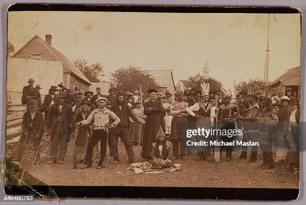 Russian priest and Russian settlers gather with Native Americans in traditional dress in the town of Sitka, Alaska, ca. 1900.