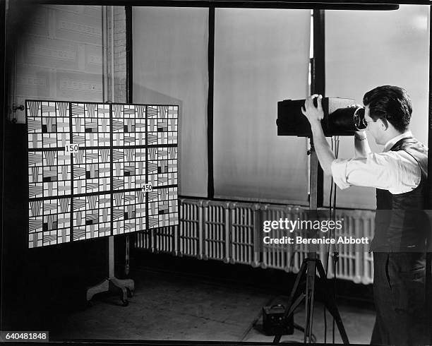 An unidentified television engineer uses an electronic telescope to measure image distortion with a pattern board, Camden, New Jersey, late 1950s....