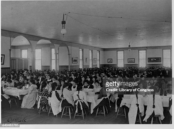 Seperated by gender, here Native American students sit down to a meal. The United States Indian School in Carlisle Pennsylvania opened in 1879. It's...