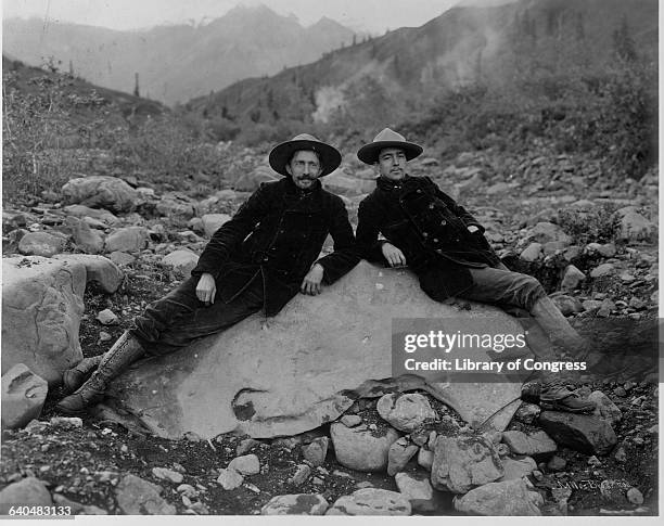 Two men recline on a large nugget of pure native copper in the bed of Nugget Creek, near Valdez, Alaska. | Location: near Valdez, Alaska Territory,...