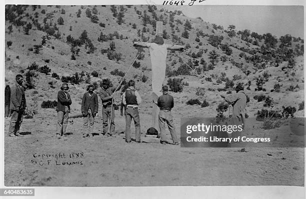 Pueblo Indians errect a crude crucifix in the desert, New Mexico, ca. 1888-1890.